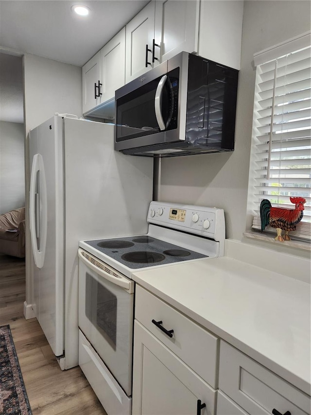 kitchen with white cabinetry, white electric range, and light hardwood / wood-style flooring