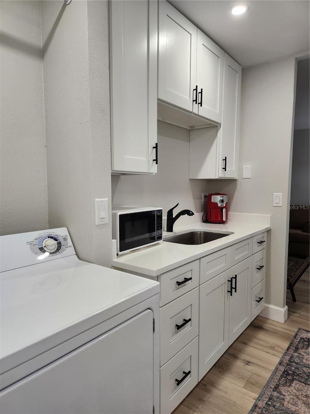 kitchen featuring washer / dryer, sink, white cabinets, and light wood-type flooring