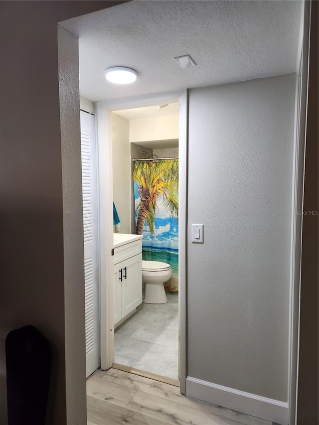 bathroom with vanity, wood-type flooring, a textured ceiling, and toilet