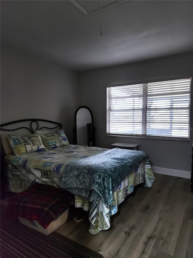 bedroom with multiple windows and dark hardwood / wood-style floors