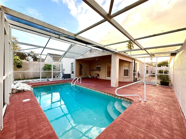 view of swimming pool featuring a patio, ceiling fan, and glass enclosure