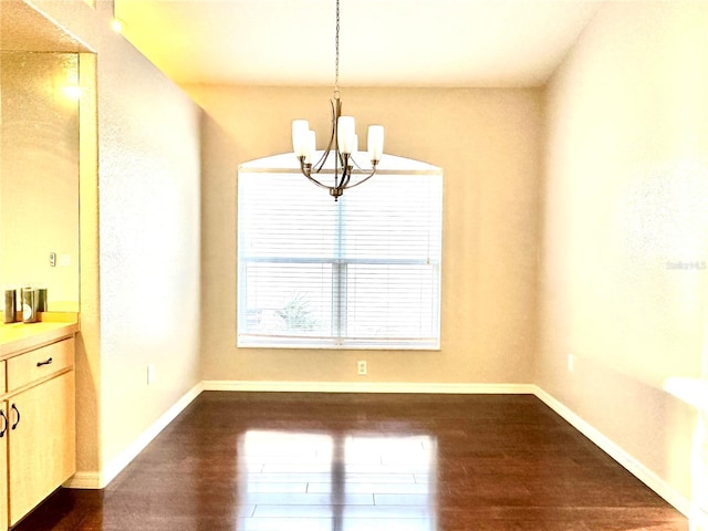 unfurnished dining area with an inviting chandelier and dark hardwood / wood-style flooring