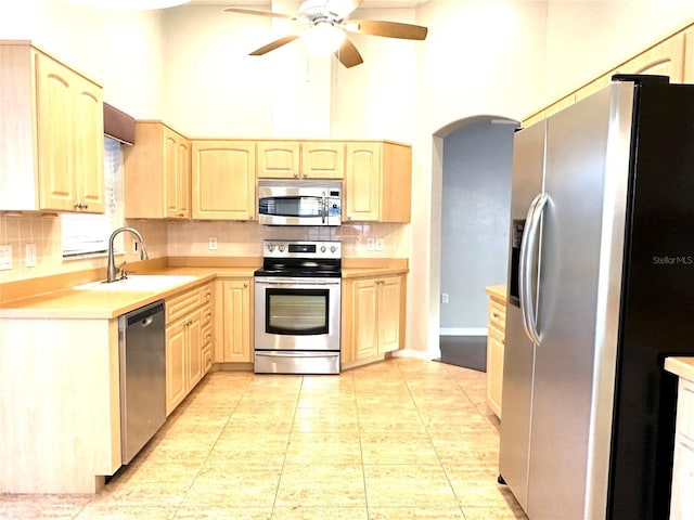 kitchen with sink, decorative backsplash, a high ceiling, stainless steel appliances, and light brown cabinets