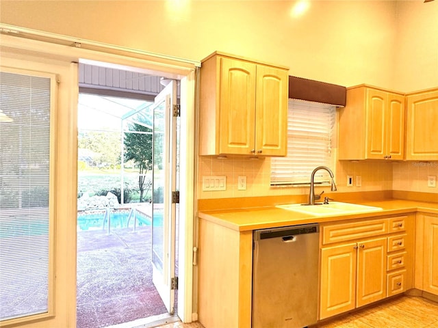 kitchen featuring stainless steel dishwasher, sink, and backsplash