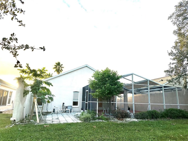 back of property with a patio, glass enclosure, and a lawn