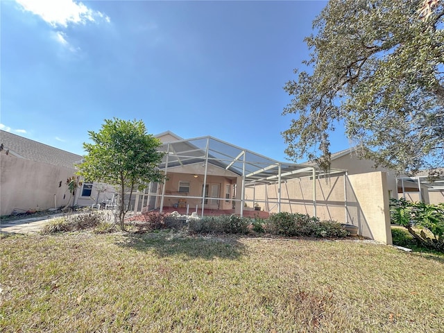 back of property featuring a yard and glass enclosure