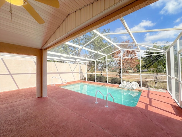 view of swimming pool with ceiling fan, glass enclosure, and a patio area