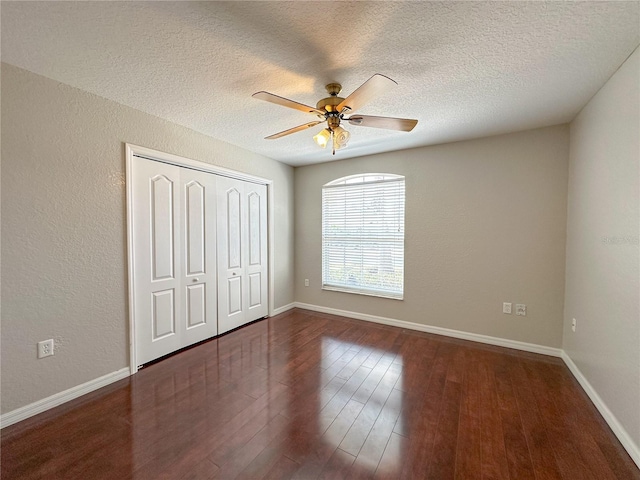 unfurnished bedroom featuring ceiling fan, dark hardwood / wood-style floors, a textured ceiling, and a closet