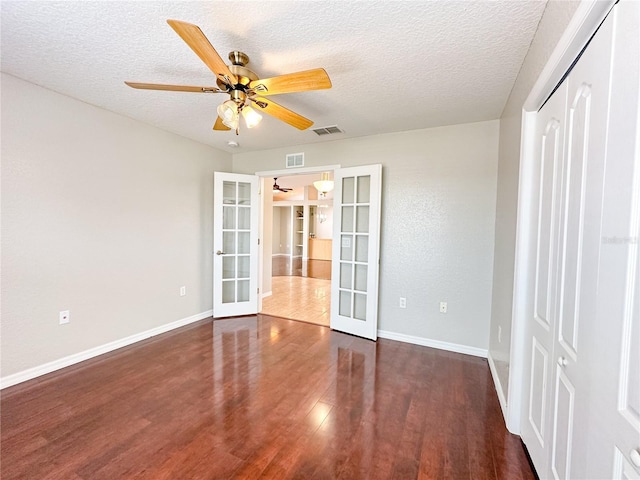 spare room with ceiling fan, dark wood-type flooring, a textured ceiling, and french doors