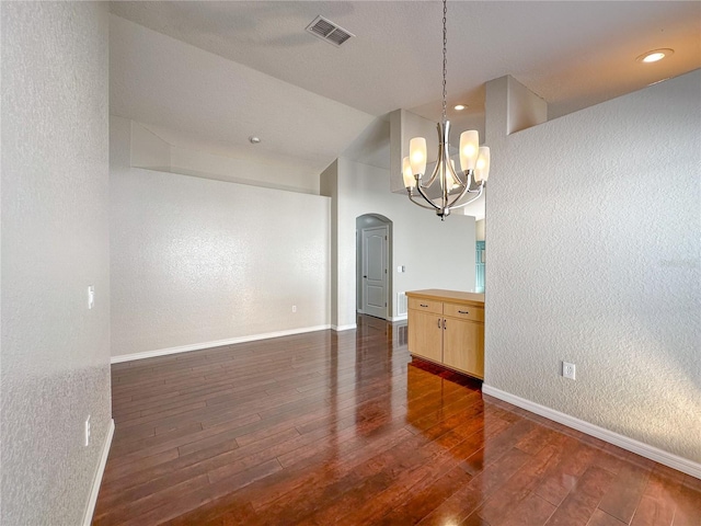 spare room featuring dark hardwood / wood-style floors and a chandelier