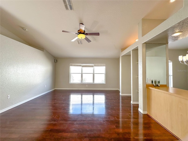 empty room with ceiling fan, lofted ceiling, dark hardwood / wood-style floors, and a textured ceiling