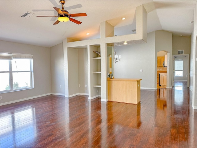 unfurnished living room featuring vaulted ceiling, dark hardwood / wood-style floors, ceiling fan, and built in shelves