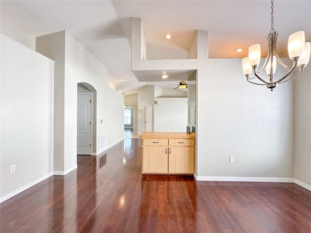 interior space featuring lofted ceiling, dark hardwood / wood-style flooring, and ceiling fan with notable chandelier