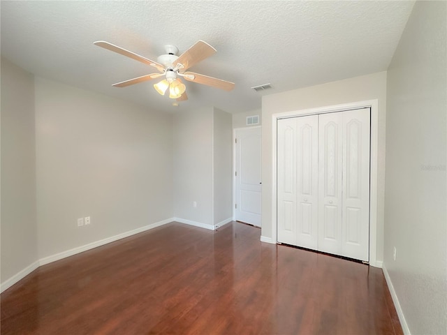 unfurnished bedroom with a closet, dark hardwood / wood-style floors, a textured ceiling, and ceiling fan