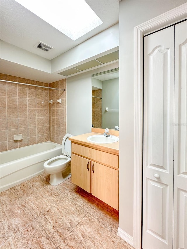 full bathroom featuring vanity, toilet, tiled shower / bath, and a skylight