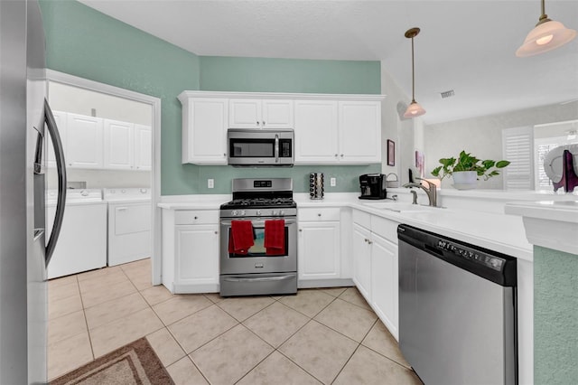 kitchen with hanging light fixtures, washer and clothes dryer, stainless steel appliances, and sink