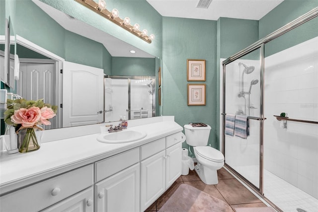 bathroom with vanity, tile patterned floors, a shower with door, and toilet