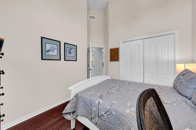 bedroom with a towering ceiling, hardwood / wood-style floors, and a closet