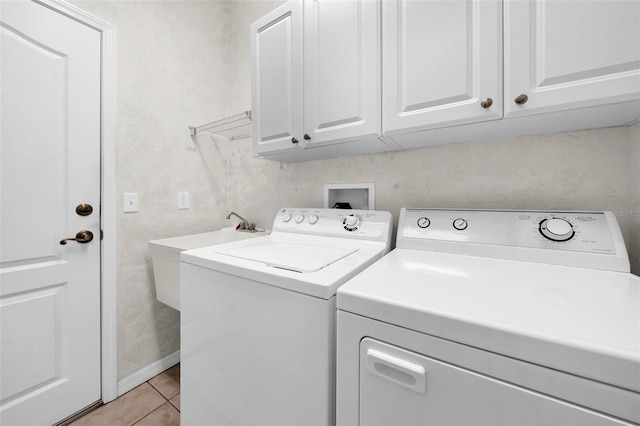 clothes washing area with cabinets, washing machine and dryer, and light tile patterned floors