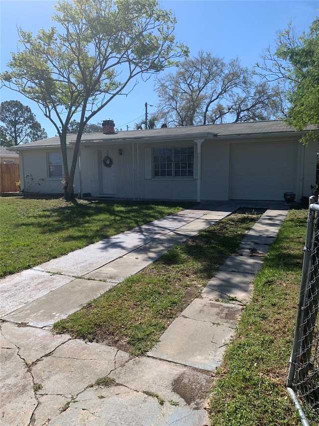 view of front of property featuring fence, an attached garage, a chimney, a front lawn, and concrete driveway