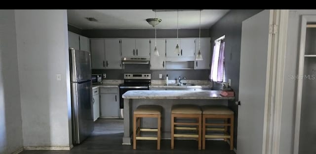 kitchen with a kitchen breakfast bar, kitchen peninsula, pendant lighting, stainless steel appliances, and white cabinets