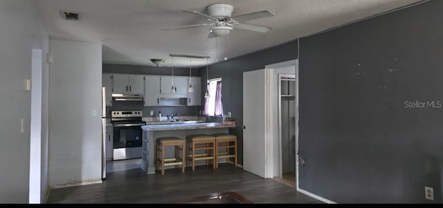 kitchen with decorative light fixtures, a breakfast bar area, white cabinets, stainless steel range with electric stovetop, and ceiling fan