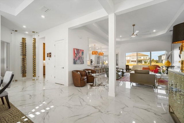 entrance foyer featuring ceiling fan with notable chandelier and a tray ceiling