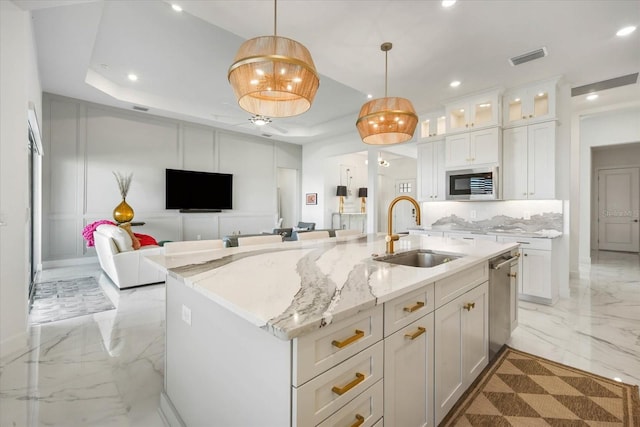 kitchen featuring a center island with sink, sink, pendant lighting, and white cabinets