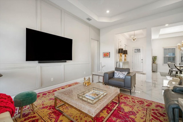 living room with a tray ceiling and a chandelier