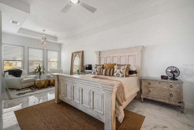 bedroom with ceiling fan with notable chandelier and a raised ceiling