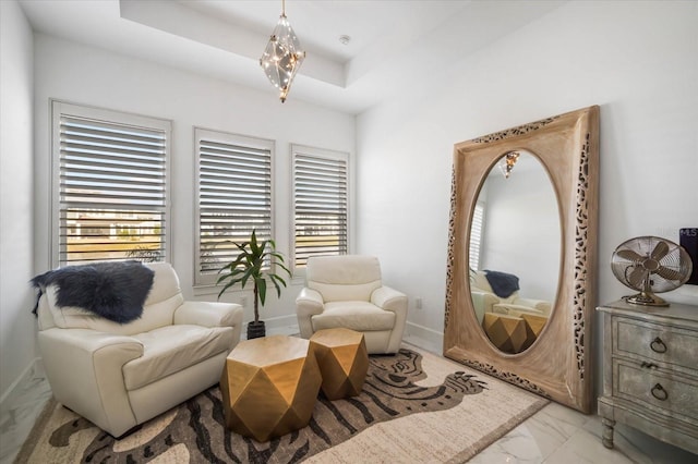 sitting room featuring a raised ceiling and an inviting chandelier