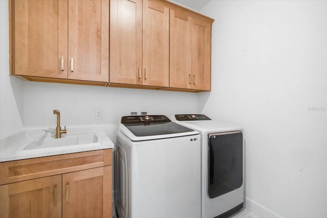 washroom featuring washer and dryer, sink, and cabinets