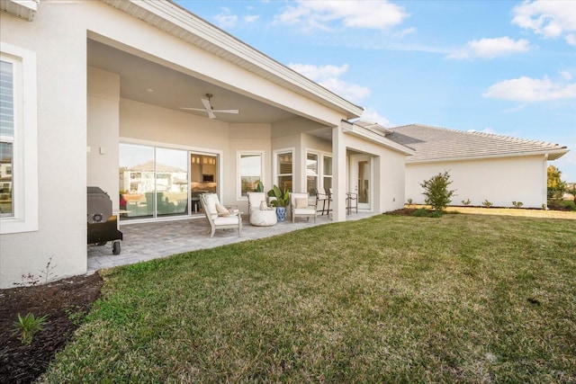 back of property featuring ceiling fan, a yard, and a patio