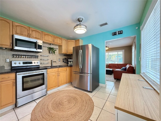 kitchen featuring stainless steel appliances, decorative backsplash, and light tile patterned floors