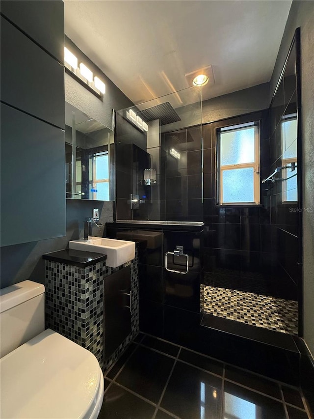 bathroom with a tile shower, vanity, tile patterned floors, and toilet