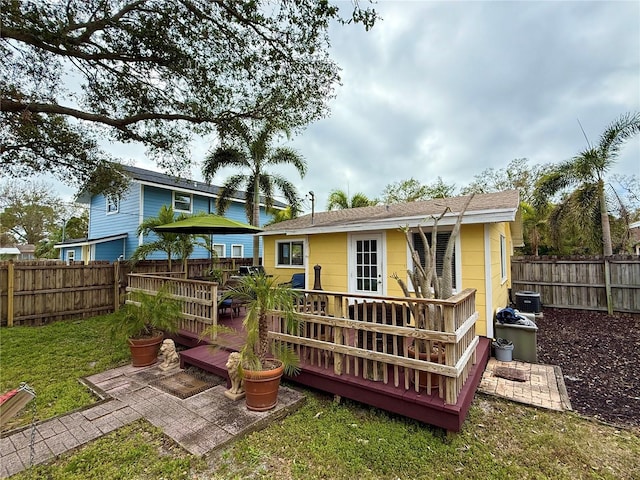 rear view of house with cooling unit, a wooden deck, and a yard