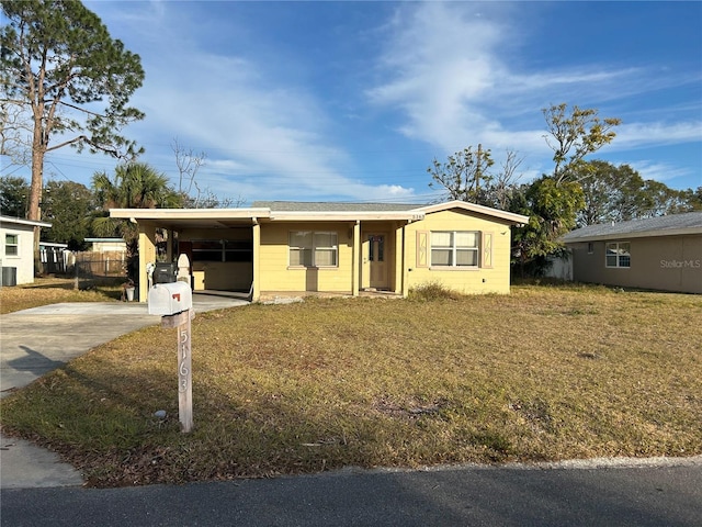 ranch-style house featuring a carport, central AC unit, and a front lawn