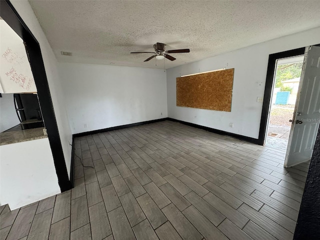 unfurnished room with a textured ceiling, dark wood-type flooring, and ceiling fan