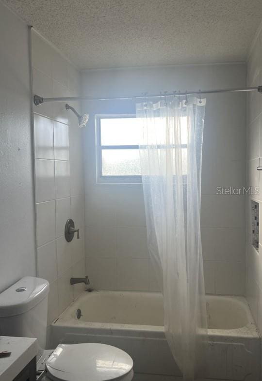 full bathroom with shower / tub combo with curtain, vanity, toilet, and a textured ceiling