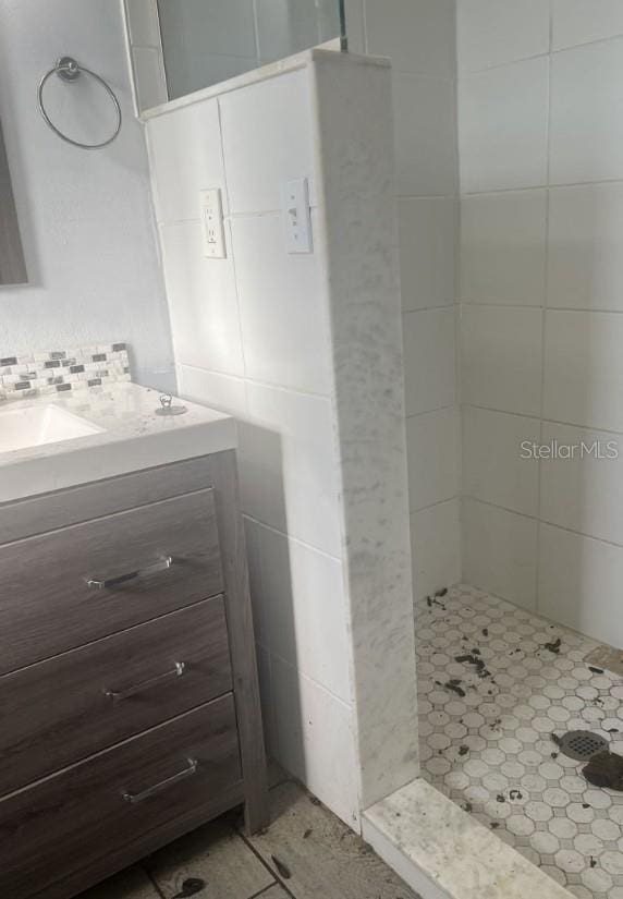 bathroom featuring tiled shower and vanity