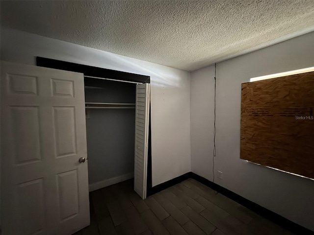 unfurnished bedroom with a closet, dark hardwood / wood-style floors, and a textured ceiling