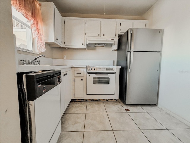 kitchen with electric range oven, light tile patterned floors, stainless steel refrigerator, white dishwasher, and white cabinets