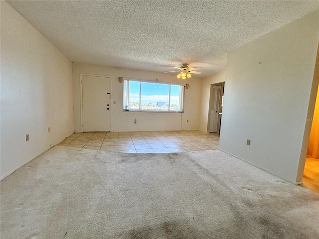 unfurnished room featuring ceiling fan, light colored carpet, and a textured ceiling