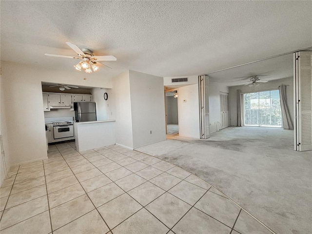 unfurnished living room featuring light carpet, a textured ceiling, and ceiling fan