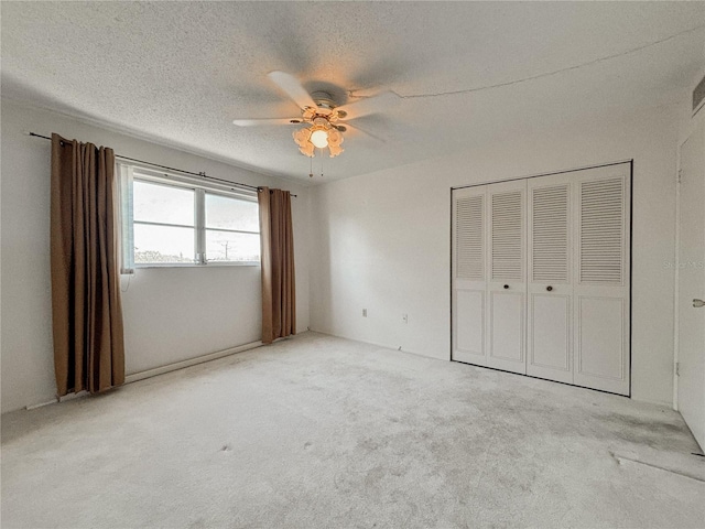 unfurnished bedroom featuring ceiling fan, a closet, light carpet, and a textured ceiling