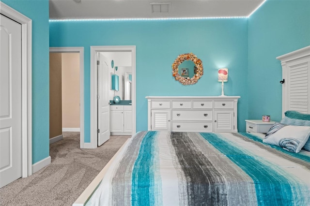 bedroom with light colored carpet and ensuite bath