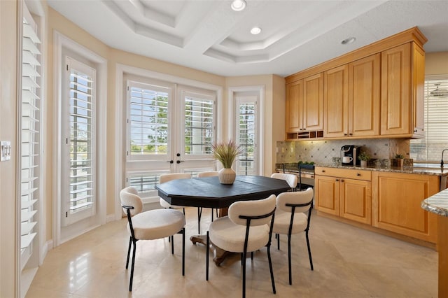 dining area with a tray ceiling, light tile patterned floors, and french doors