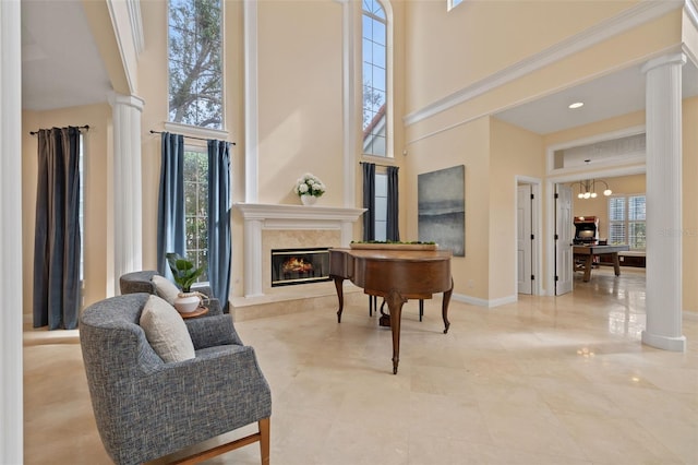 sitting room with ornate columns, a premium fireplace, plenty of natural light, and a high ceiling