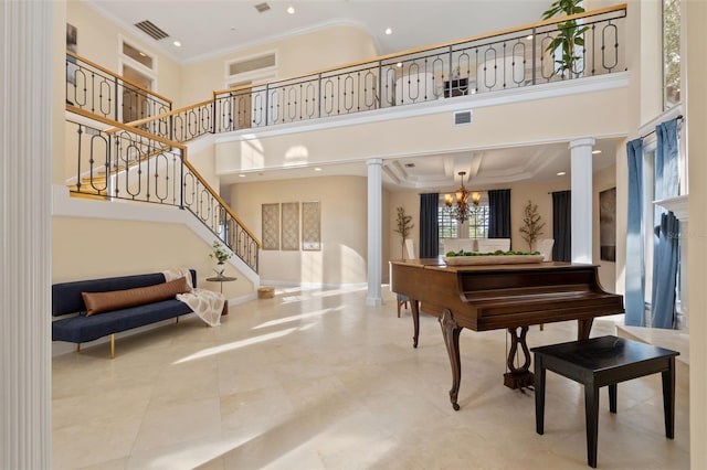 misc room featuring crown molding, a towering ceiling, a chandelier, and decorative columns