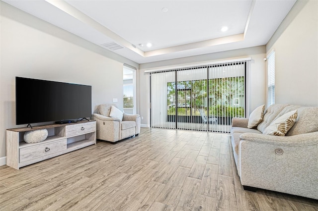 living room featuring a raised ceiling and light hardwood / wood-style flooring